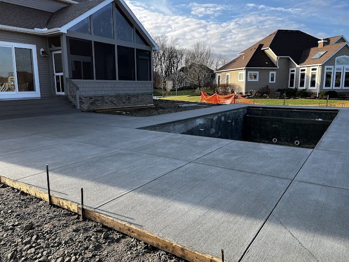 A concrete patio with a pool in the middle