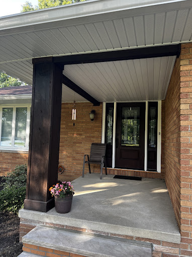 A front porch with a chair and flowers on the steps